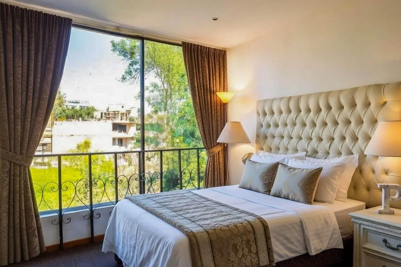 Recámara principal con cama king size, cabecera acolchada y ventanal panorámico con vistas al jardín en casa Bosques de las Lomas