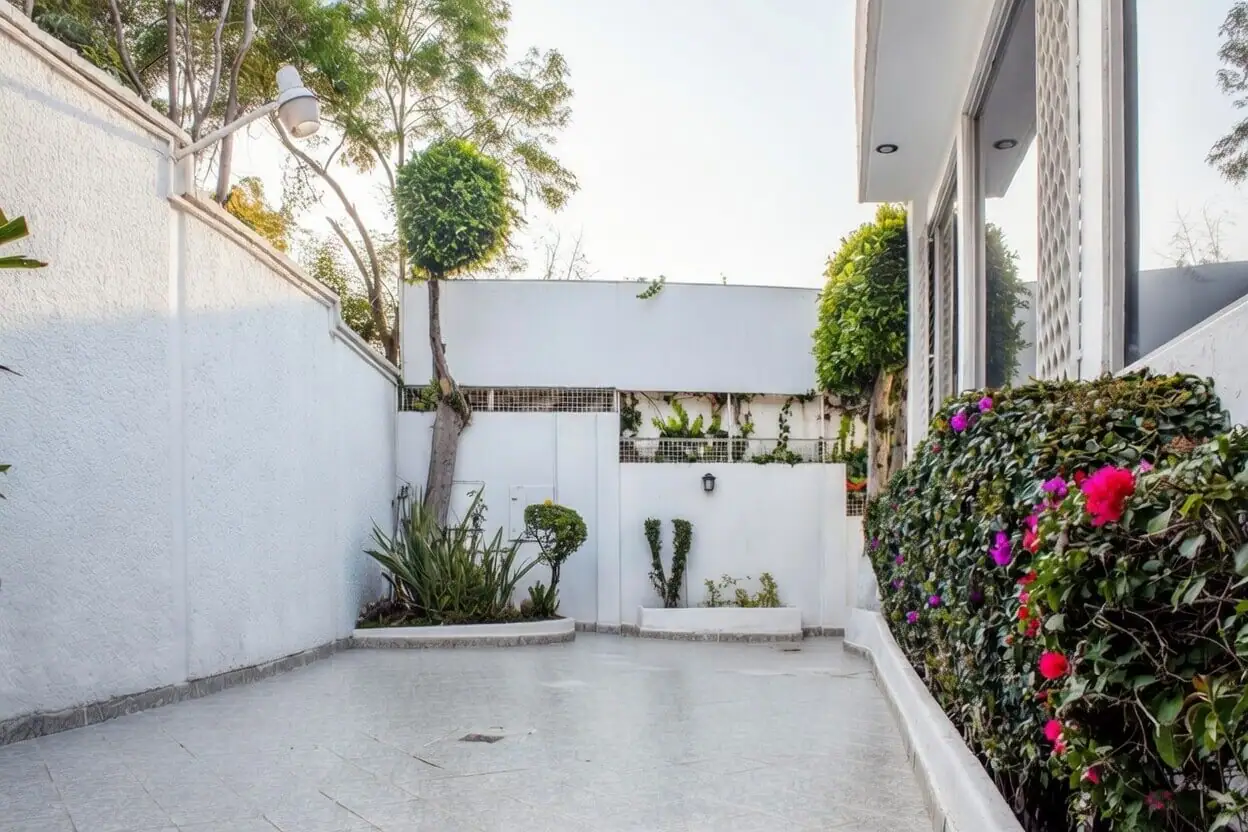 Entrada principal al jardín de casa de lujo en Bosques de las Lomas, fachada moderna con vegetación y camino de acceso